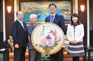 羅達生副市長(右二)致贈高雄美濃油紙傘予美濃市武藤鉄弘市長(左二)、山口育男議長(左一),期盼深化雙邊文化工藝交流合作(高雄市政府 提供)