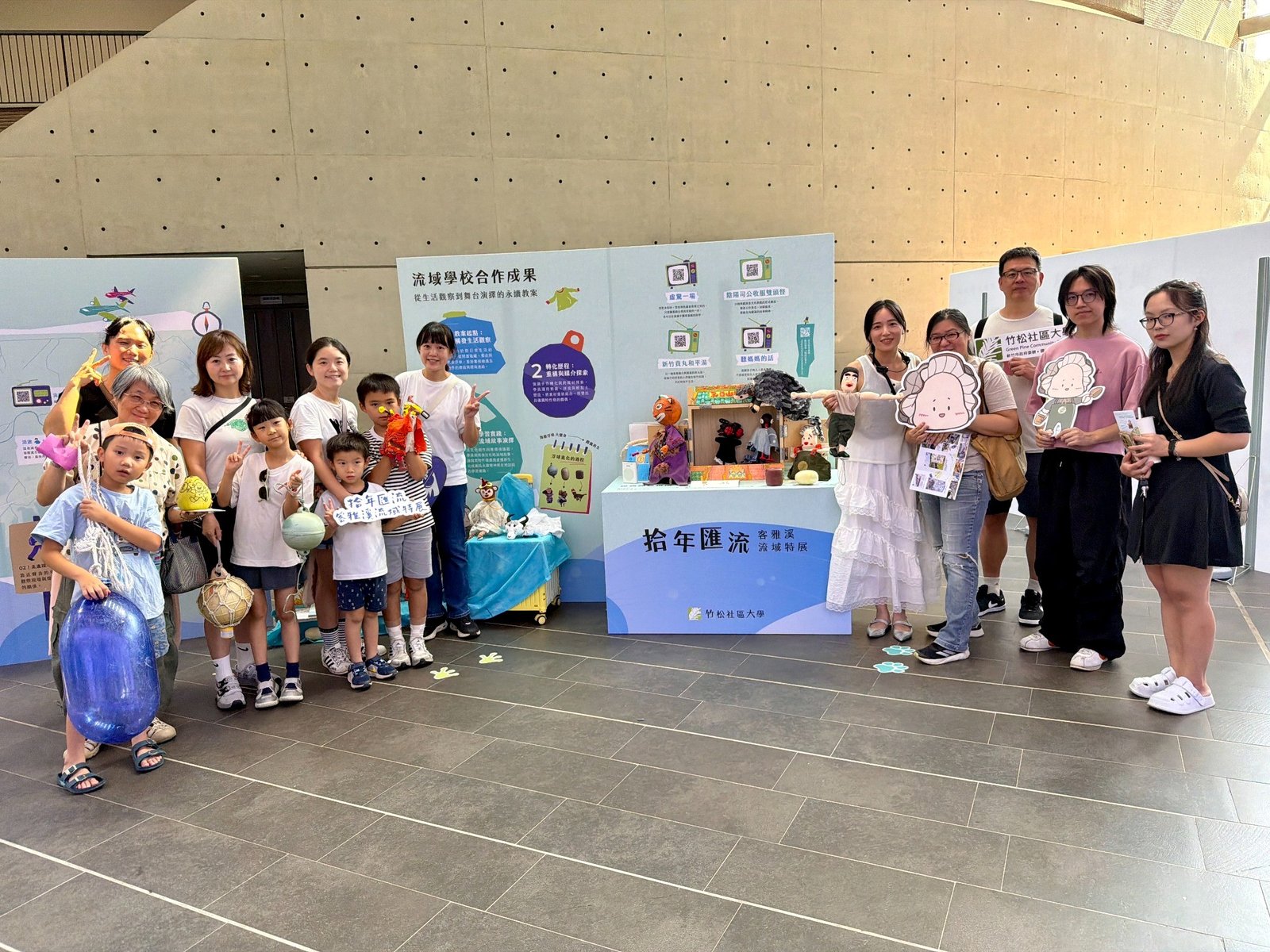 竹松社區大學美感教育老師彭雅琪與學員及參與民眾在「拾年匯流—客雅溪流域特展」展區合影,現場展示以海廢浮球、舊衣物等素材製作的戲偶及創作作品。(新唐人亞太電視)