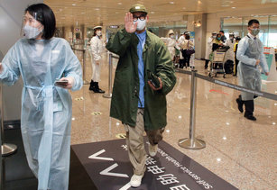 韓團酷龍成員具俊曄（中）9日上午抵達桃園國際機場，向現場採訪記者揮手致意，由服務人員引導進行健康宣告，再到發燒篩檢站旁的房間進行深喉唾液採檢。（圖／中央社）