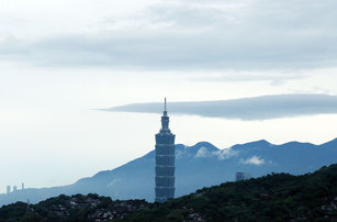 中央氣象局表示16日中部以北沿海地區較易下雨、 降雨時間較長，南部偶爾有零星降雨；氣溫則各地感受仍溫暖偏熱。圖為從北市南區遠眺101大樓，雲層已逐漸遠離。（圖／中央社）