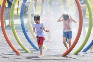 適逢24節氣中的大暑，23日各地天氣晴朗炎熱，中央氣象局上午持續發布18縣市高溫燈號資訊。圖為台北市大佳河濱公園，小朋友在戲水區玩水消暑。（圖／中央社）