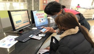 健保服務人員協助外籍生以行動電話快速綁定健保。（中央健康保險署北區業務組提供）