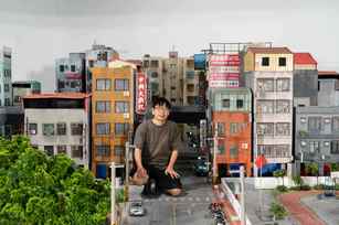 張立人與《戰鬥之城》城市模型合影。以自身身體為比例尺、依憑記憶空間尺度搭建展場舞台。（圖／內惟藝術中心）
